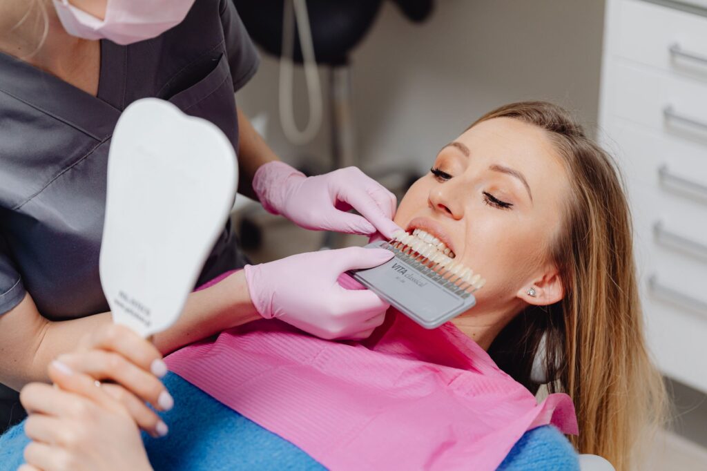 Odontóloga comparando el tono de los dientes con una guía de color antes de un blanqueamiento dental